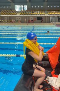 Alumna con chaleco salvavidas subiendo a la balsa en la práctica de amerizaje en piscina